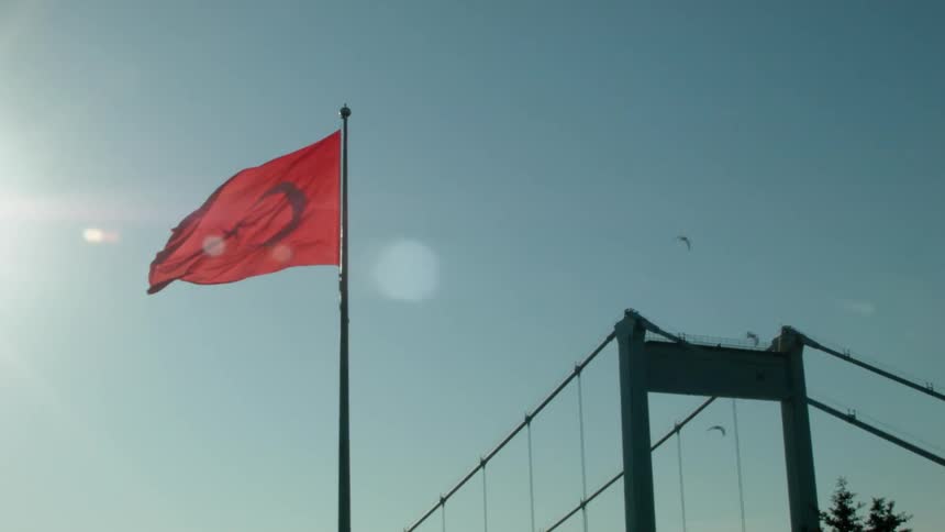 A flag flies high in the clear sky