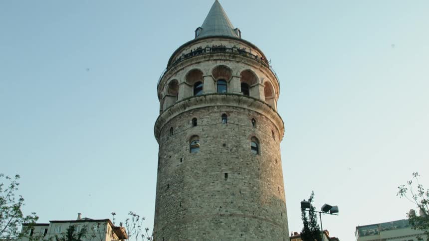 Birds fly past a tall stone tower on a sunny day