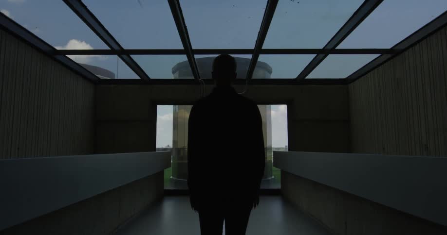 Man standing in an office building looking out a window