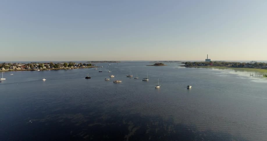 A fleet of boats are sitting in water between two bodies of land