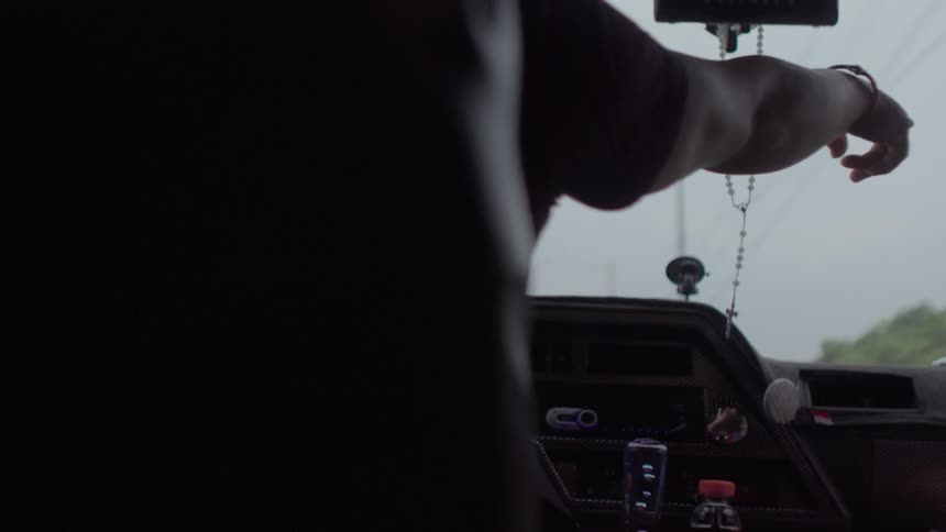 A person points out the windshield as they drive