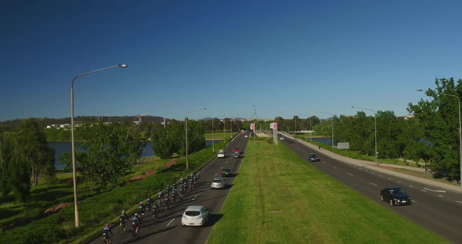 The road has cars and many people on bicycles traveling