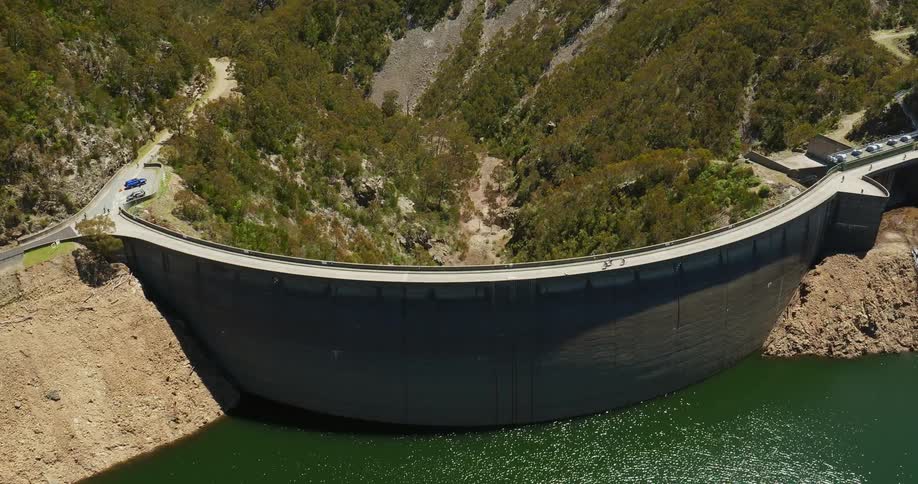 Three people ride bikes across a dam