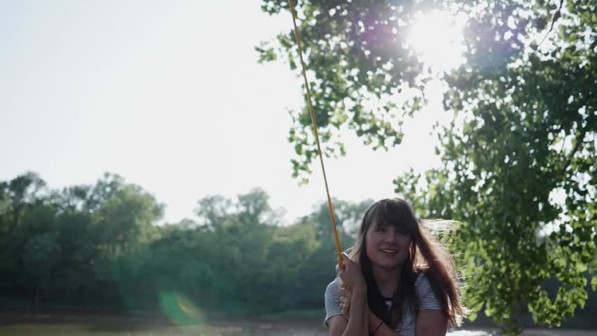 Young woman holds on to a rope as she swings