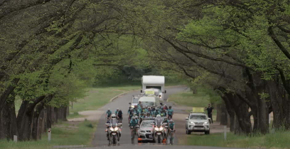 A group of bicyclists are led down a street by police