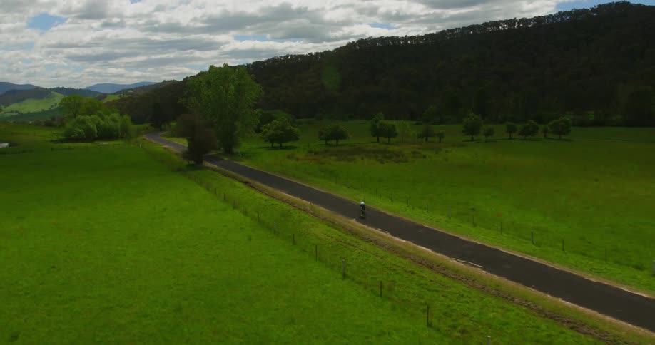 A cyclists rides along a rural road on a cloudy day