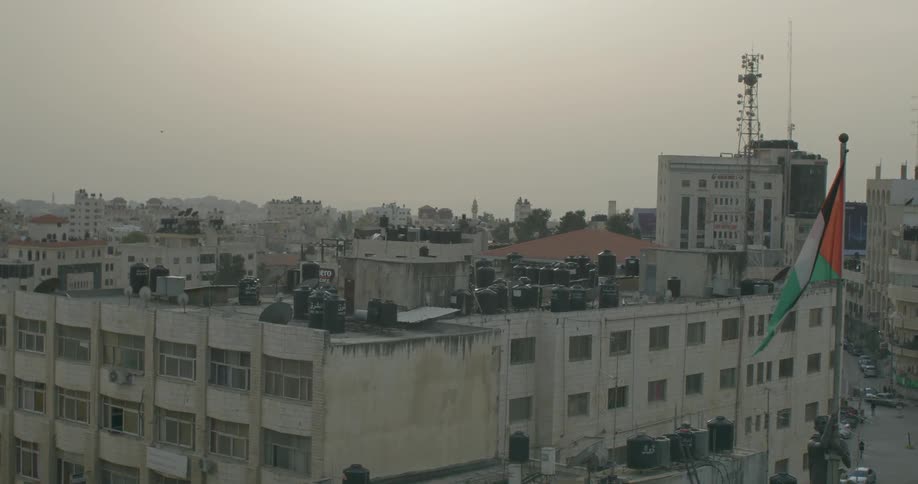 A flag waves high above buildings