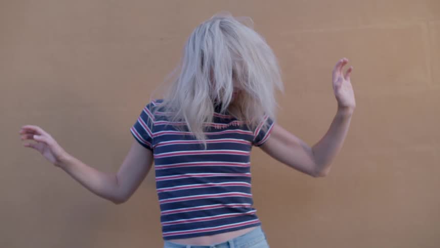 A woman gyrates by a wall