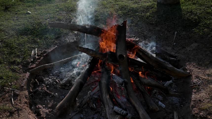 A campfire burns in the daylight
