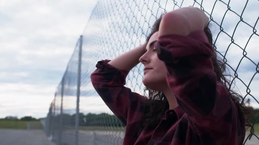 Person sitting against a chain link fence