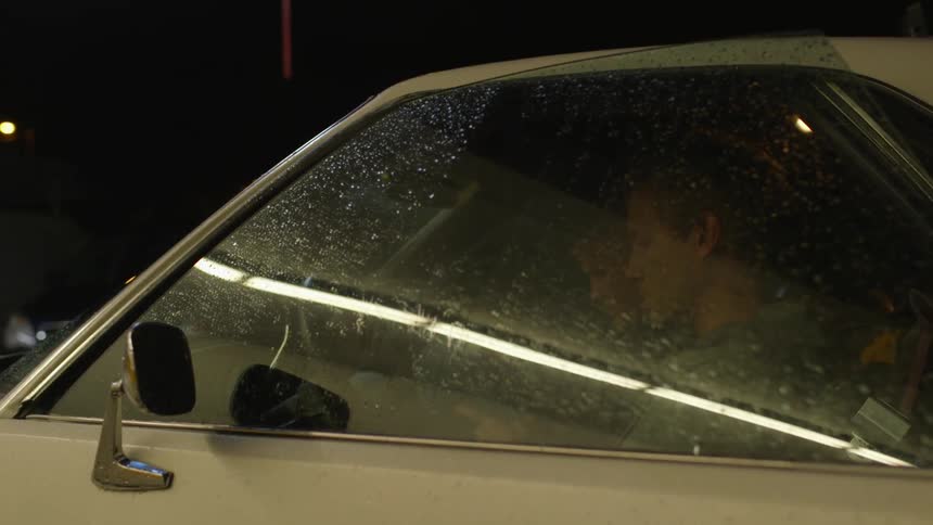 Person sitting inside a white car at night