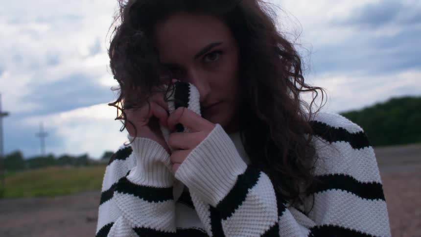 A woman cuddles up with her sweater outside