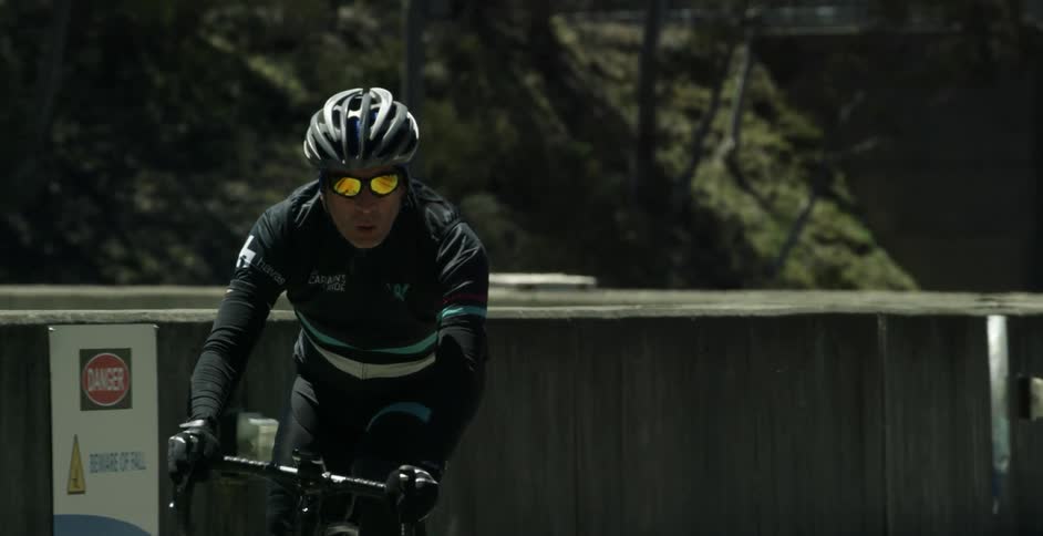Bicyclists are riding on a road with a pilot car