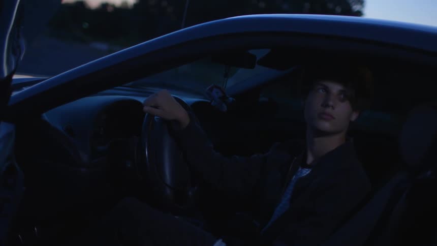 Young man sits inside a car as he looks out