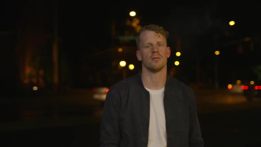 A man is lighting his cigarette and smoking at night