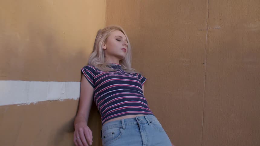 A woman in a striped shirt leans against a corner