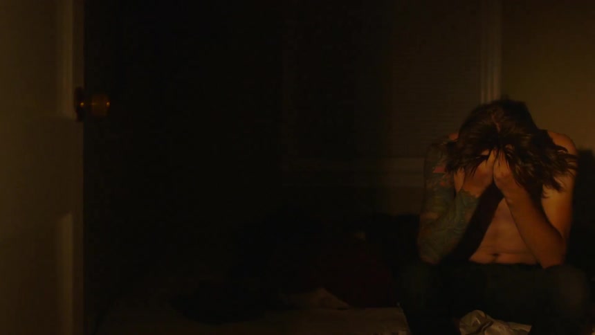 A man holds his head in his hands as he sits on a couch