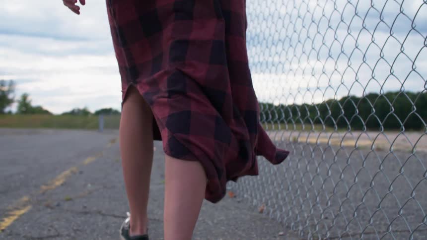 A woman walks along a chain link fence