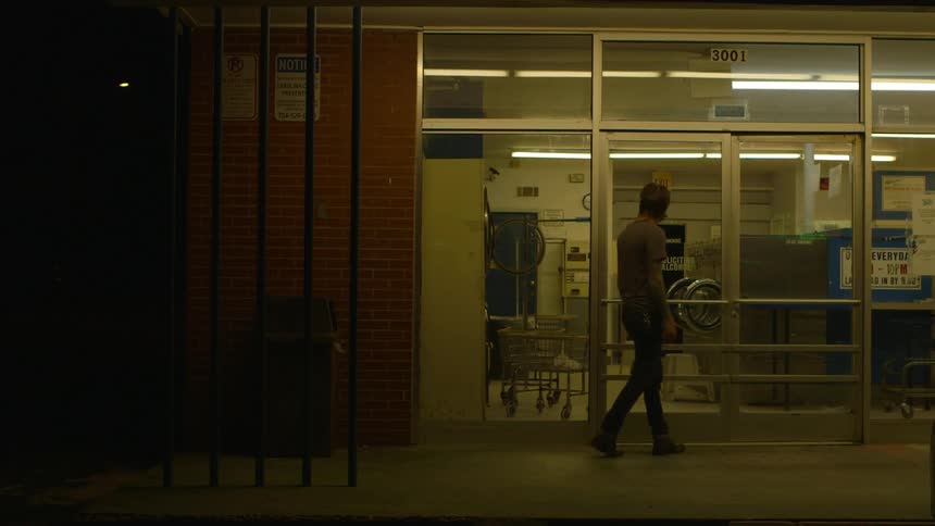 Man walks by a store window and looks inside