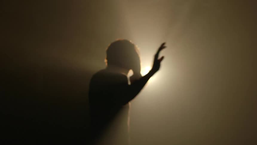 A man is trying to blot out the light from a bright light