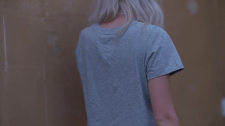 Woman in a blue t shirt walks near a wall