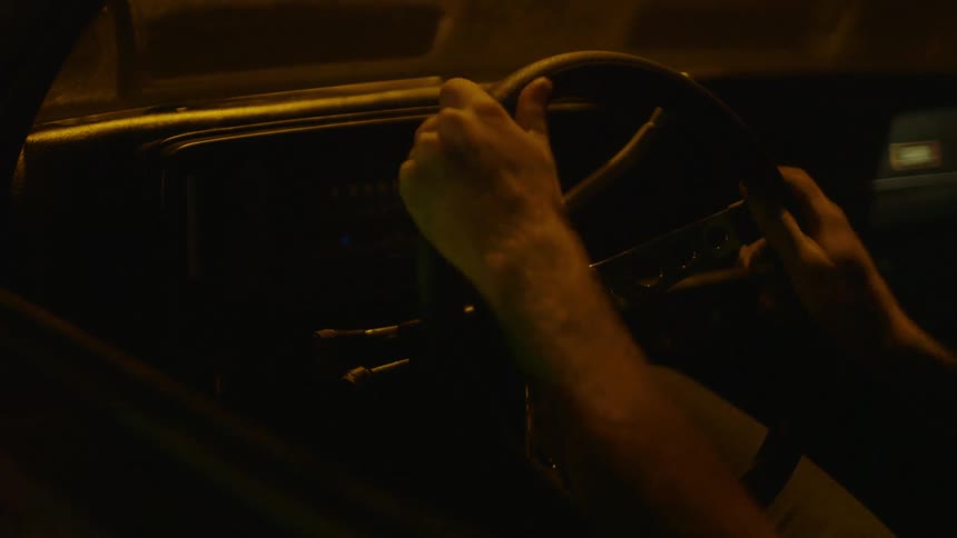 A person sits in a car and touches the steering wheel