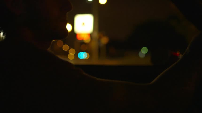 A man drives a car down the street at night