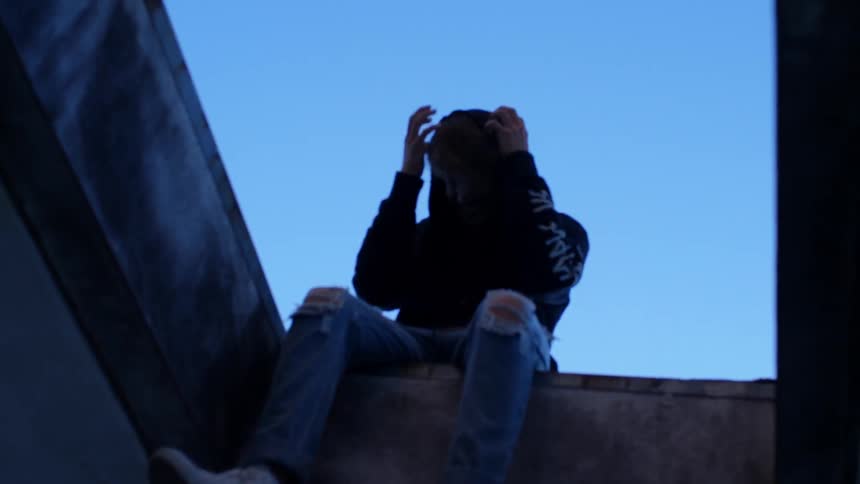 A person sits above scratching their head