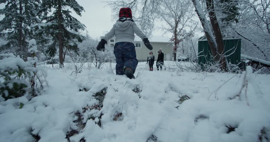 A young boy falls while walking up a snowy hill
