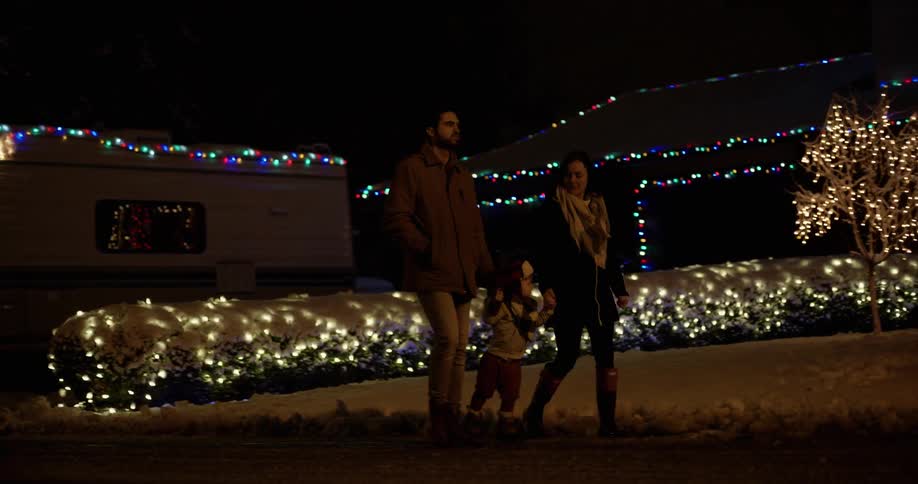 A family walks by a house decorate for christmas