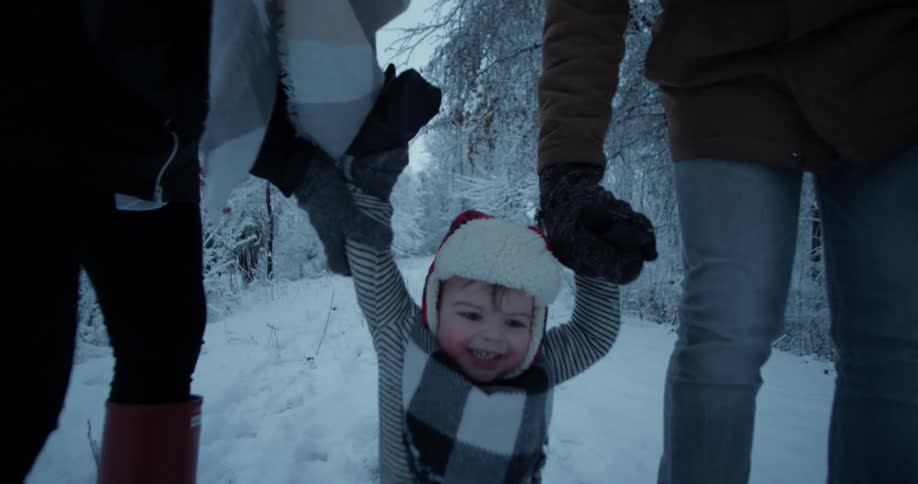 Parents lift up a boy playing around in the snow