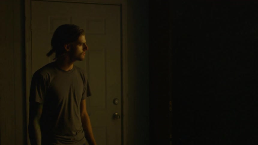 A man paces and looks around in a room