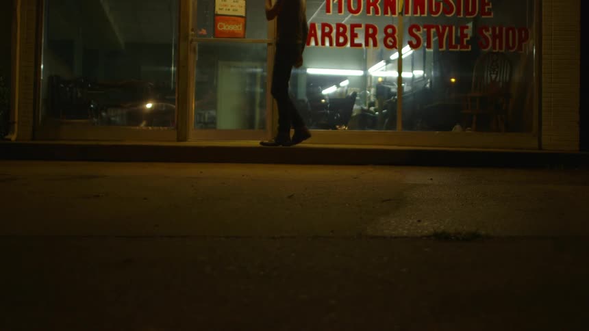 A man is dancing outside a shop at night