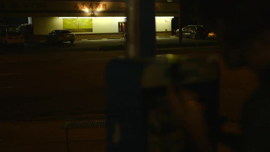 A smoking man tries to use a pay phone