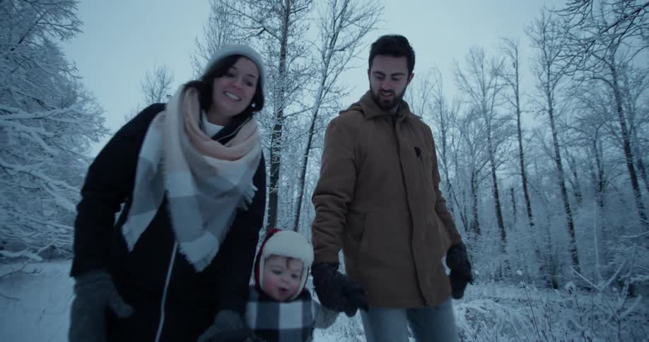Parents hold hands with their son and walk in the snow
