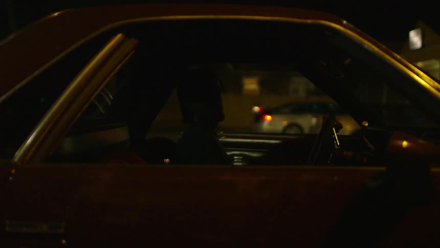 A man enters the driver seat of a car