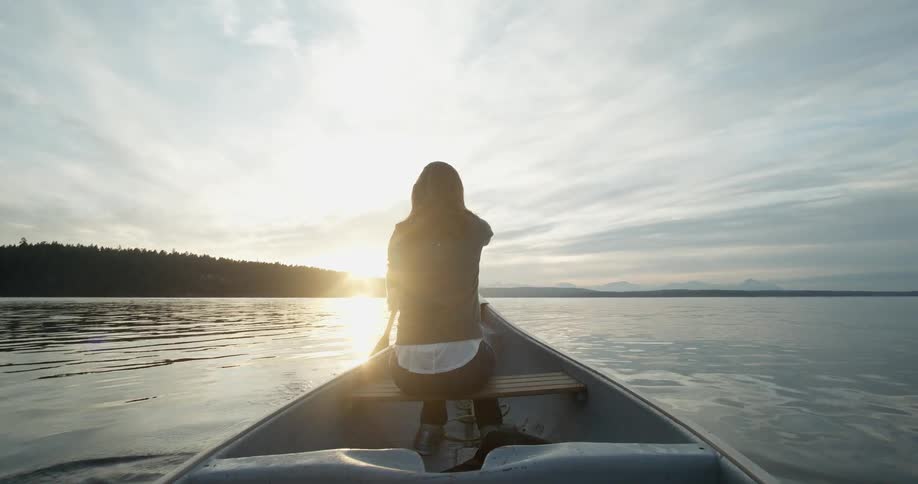 A woman is rowing a boat at sunrise