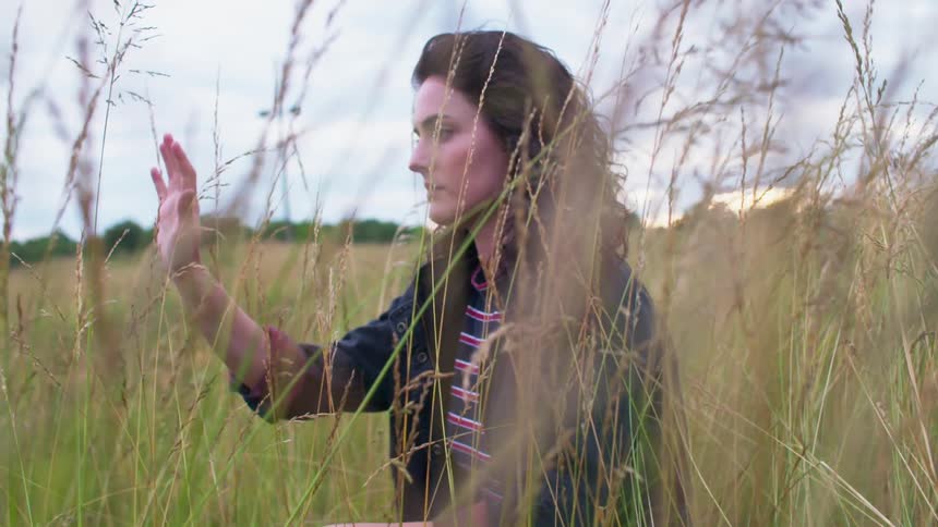 A woman is sitting in a field of tall grass