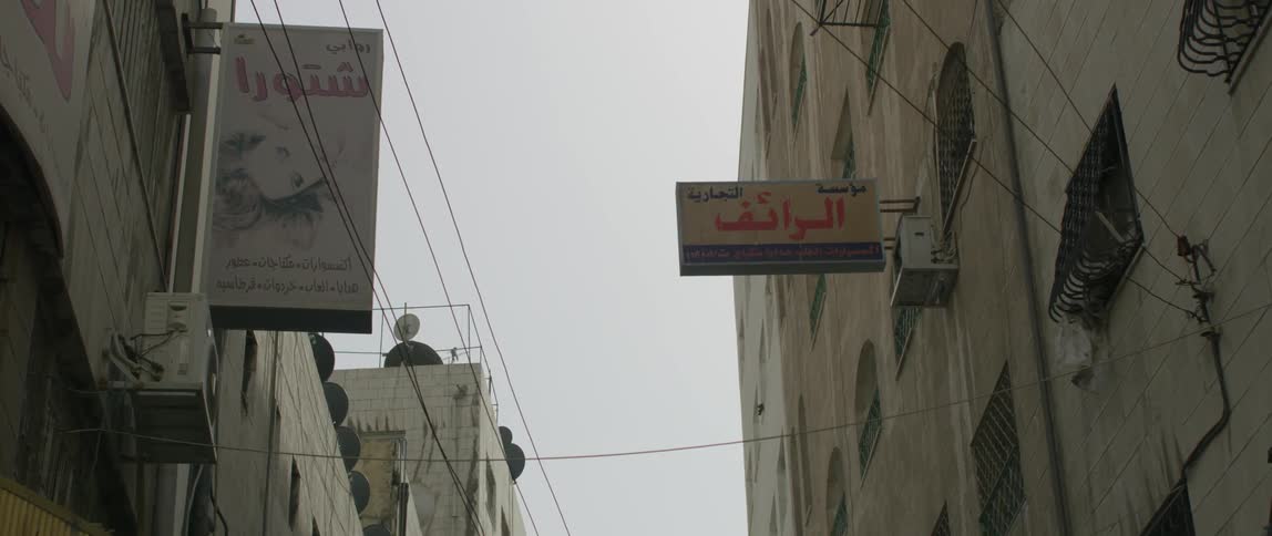 Power lines and building signs line the narrow street