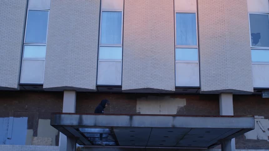 A person is sitting on a door ledge during the day