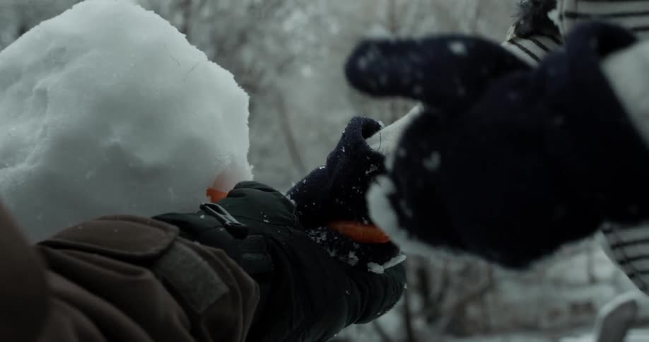 A family builds a snowman together in the snow