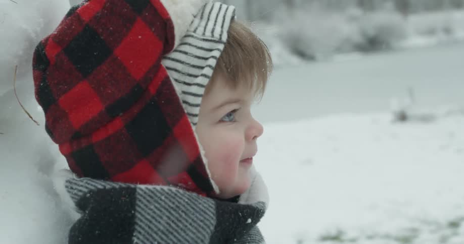 A young child is smiling as they play in the snow