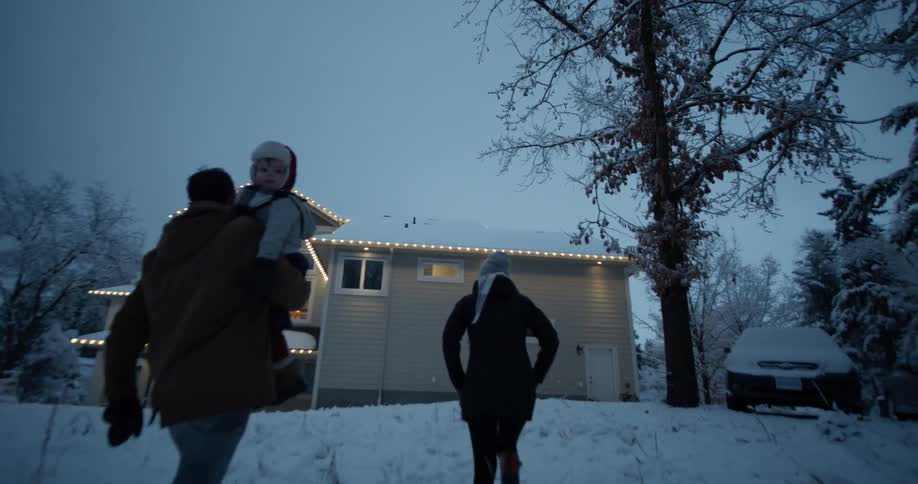 A family walks up to a house decorated for christmas