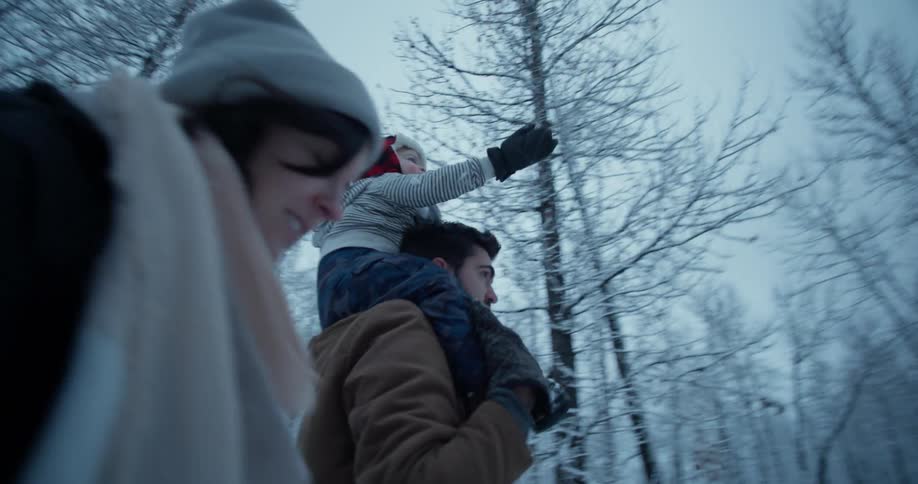A family is walking through the snow covered woods