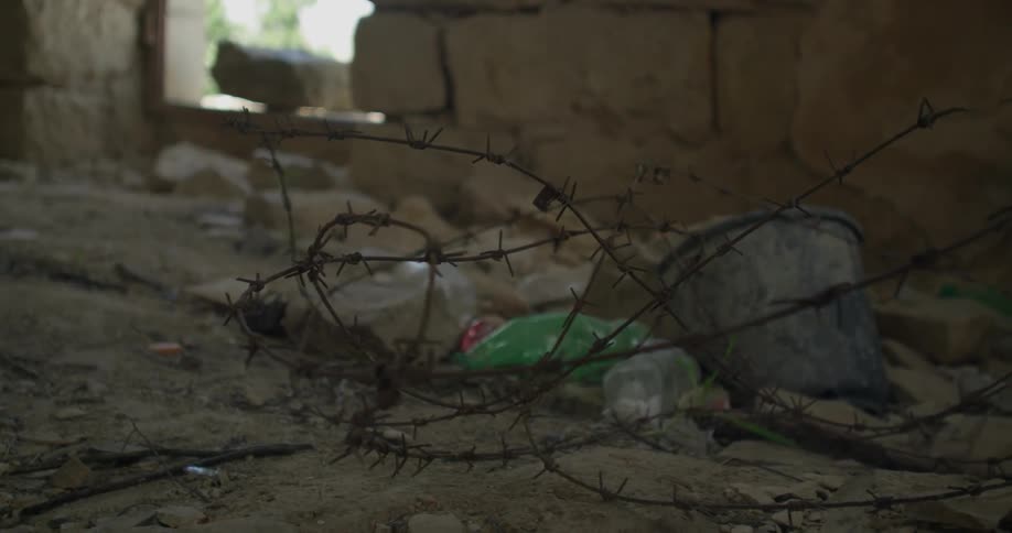 The ground is covered with debris and barb wire