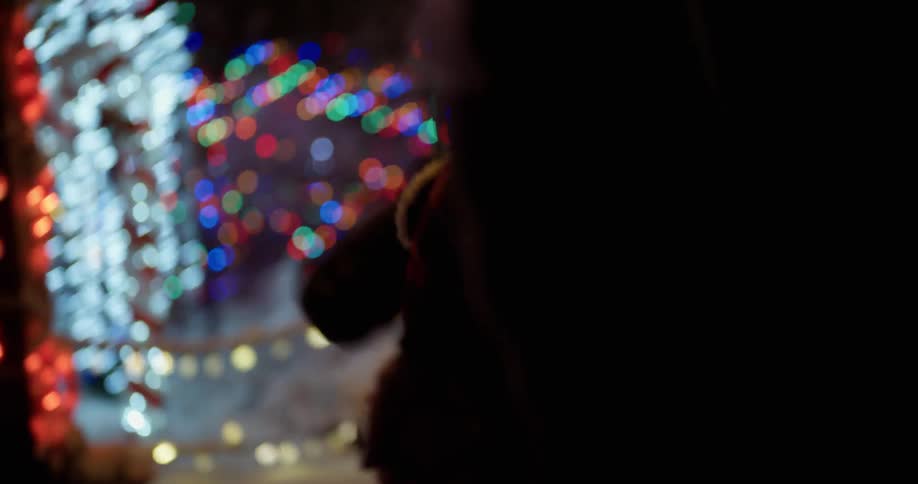 A toddler is walking with adults through a christmas light display