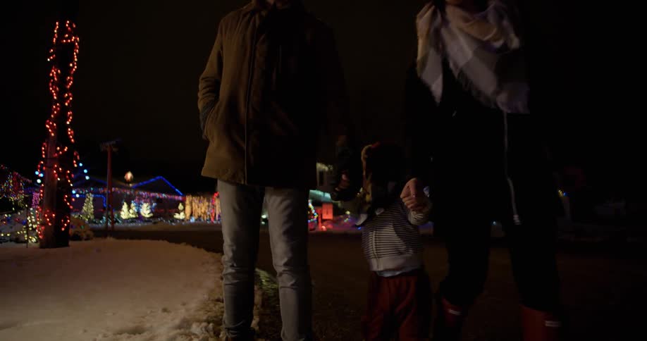 A couple hold their toddler's hands as they walk