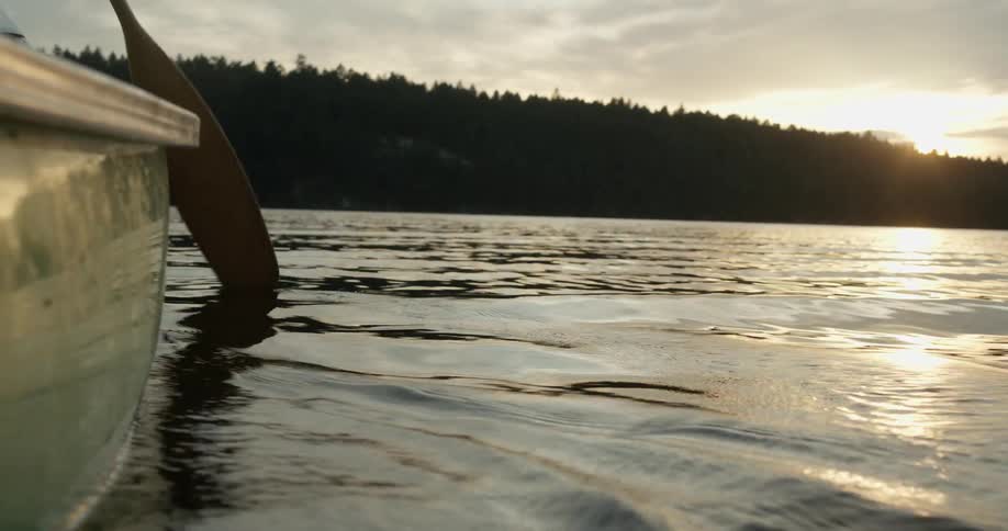 A person is paddling in the water at sunrise