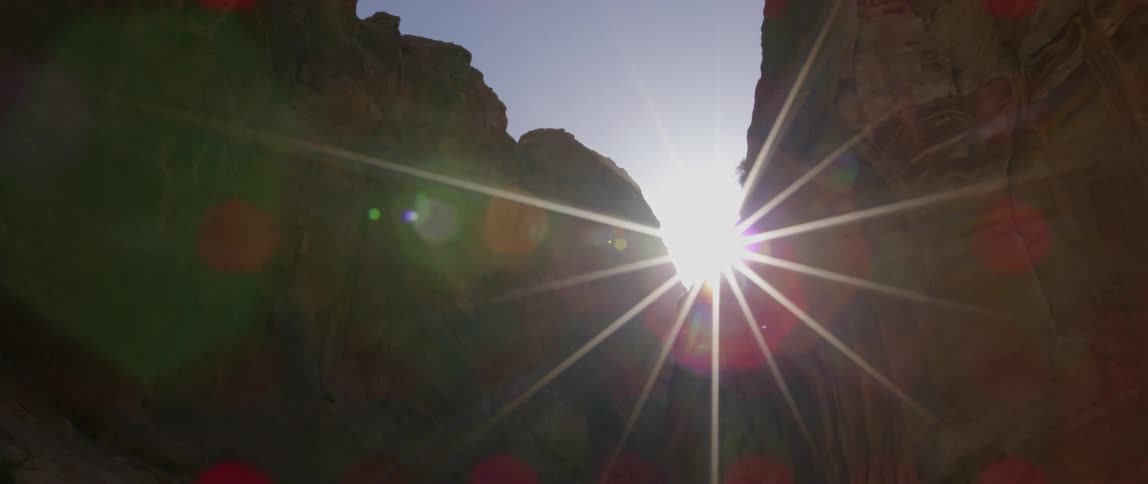 The sun peeks above the ledge of a deep gorge