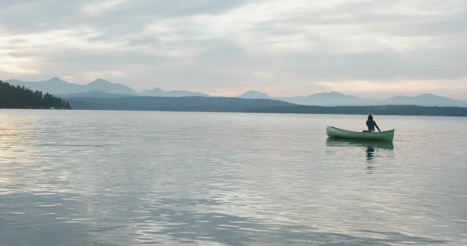 A person paddles a boat on a mountain lake